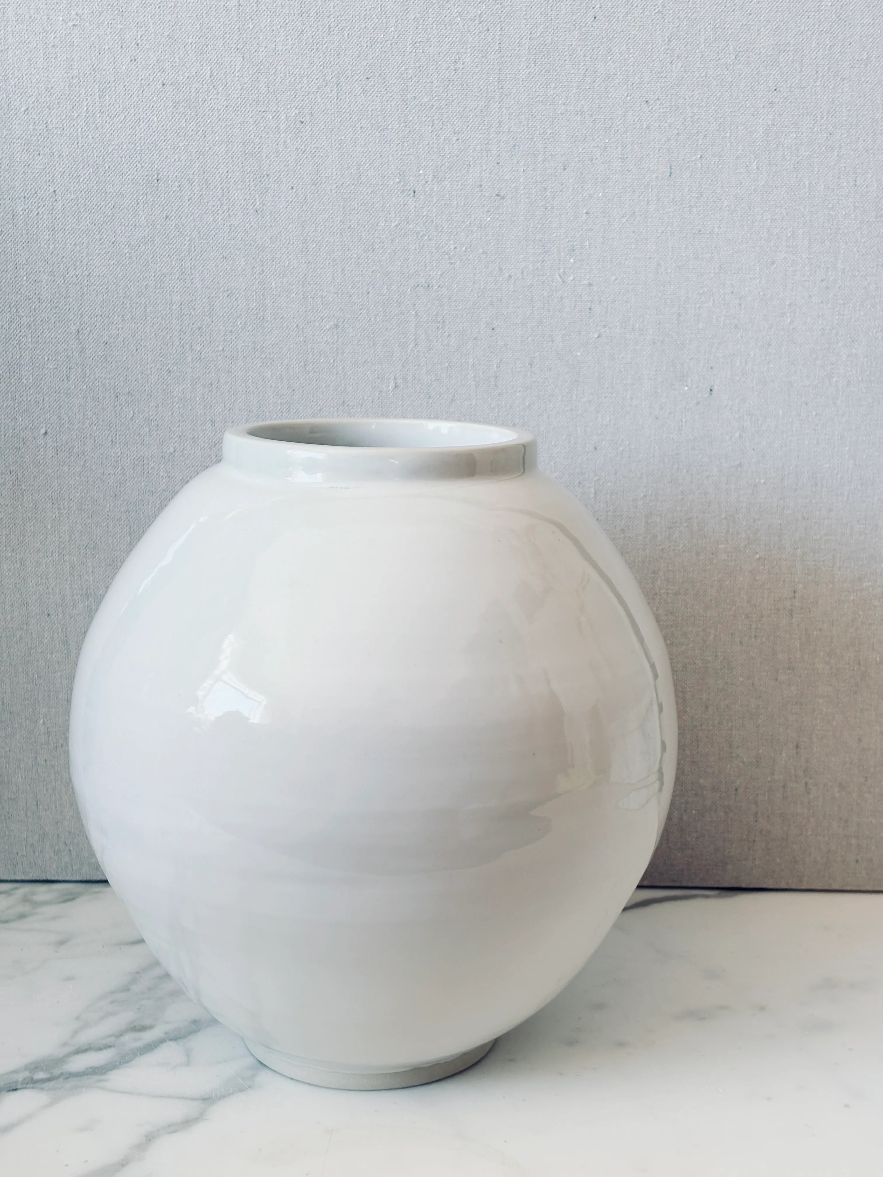 A white porcelain moon jar in soft studio light