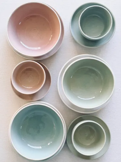 Bowls and cups arranged in blush, celadon, and sage glazes