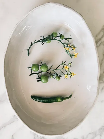 An oval white platter set with green tomato vines