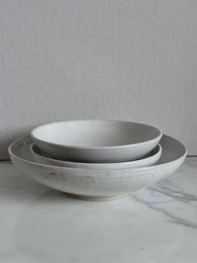 Nested speckled white bowls and a shallow plate
